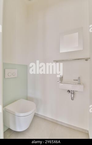 Un bagno moderno e minimalista con lavandino a parete, WC e linee pulite con tonalità neutre. Foto Stock