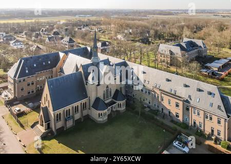 Un drone cattura la splendida architettura di un complesso di chiese con edifici adiacenti in un tranquillo contesto residenziale. Foto Stock