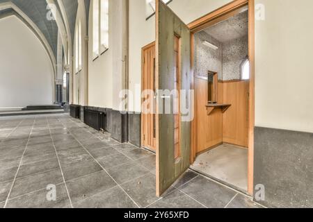 "Corridoio polveroso in un edificio abbandonato con archi in stile gotico e una porta aperta in legno che conduce ad una piccola stanza." Foto Stock