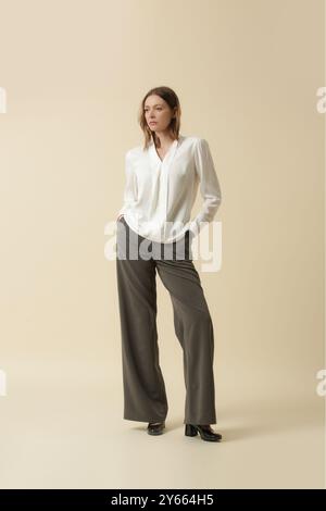 La donna indossa una blusa bianca e pantaloni grigi sartoriali. Classico stile business semplice. Ripresa in studio. Foto Stock