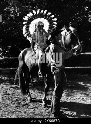 In completo abito indiano , Luta Starr è visto montato a schiena su un cavallo tenuto da marito Buck al Thunderbird Ranch , vicino a Lewes , Sussex , Inghilterra . Luta è metà indiano Cheyenne. Ottobre 1953 Foto Stock