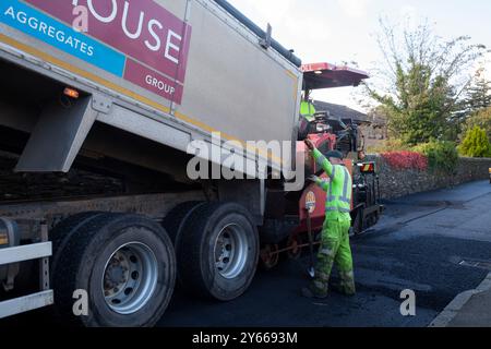 Lavoratori che riparano superfici stradali, Rhu, Scozia, che mostrano lo strato di catrame caricato con camion, Rhu, Scozia Foto Stock