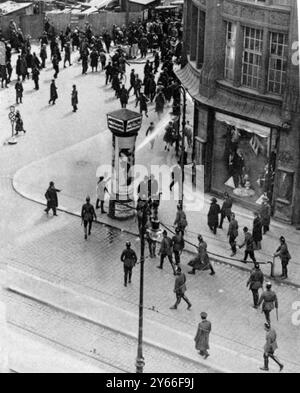 I disordini comunisti nell'acqua di Berlino erano soliti annacquare l'ardore dei comunisti di Berlino, Un poliziotto tedesco che suonava una manichetta su una folla all'angolo di Alexander Platz, mentre altri sono pronti con i manganelli maggio 1929 Foto Stock