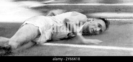 L'Agony of Jim Peters Marathon Runner giace pedinando il terreno impotente mentre cerca di coprire le ultime yard dei Giochi dell'Impero britannico e del Commonwealth del 10 agosto 1954 Foto Stock