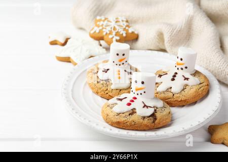 Deliziosi biscotti con pupazzi di neve fatti di marshmallow su tavola bianca, primo piano Foto Stock