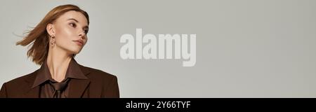 Donna bionda felice con abiti caldi marroni che posa attivamente. Foto Stock