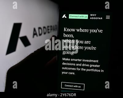 In questa illustrazione fotografica, una persona ha in mano un cellulare con la pagina Web della società di software di gestione patrimoniale statunitense Addepar Inc. Davanti al logo. Foto Stock