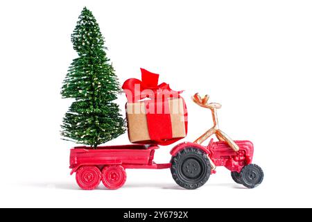 Delizioso trattore rosso decorato con un albero di Natale, una scatola regalo e una renna, che cattura l'essenza del festeggiamento e delle festività natalizie. Foto Stock