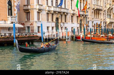 Un gondoliere guida la sua gondola con due persone godendosi un giro in gondola lungo il Canal grande a Venezia Foto Stock