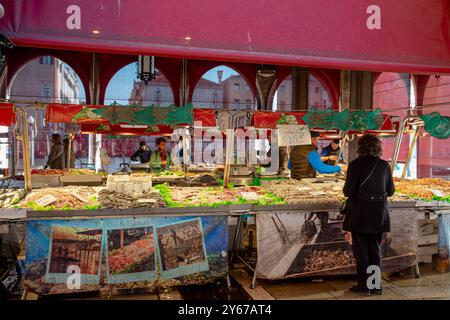 Una donna che acquista pesce fresco al mercato del pesce di Rialto nel sestiere di San Polo a Venezia Foto Stock