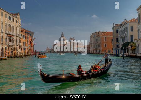 Un gondoliere guida la sua gondola con un gruppo di turisti facendo un giro in gondola sul Canal grande a Venezia Foto Stock