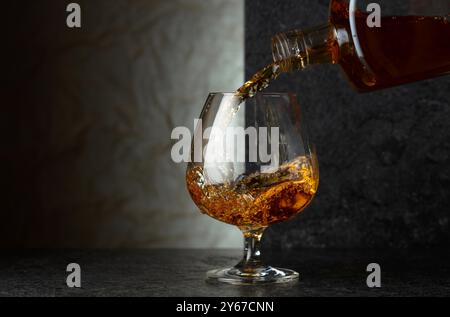 Versare il brandy da una bottiglia in un bicchiere. Spazio di copia. Foto Stock