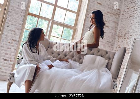 Condividere la sua felicità con un'amica. Due giovani donne attraenti che si guardano e sorridono mentre si preparano per il matrimonio Foto Stock