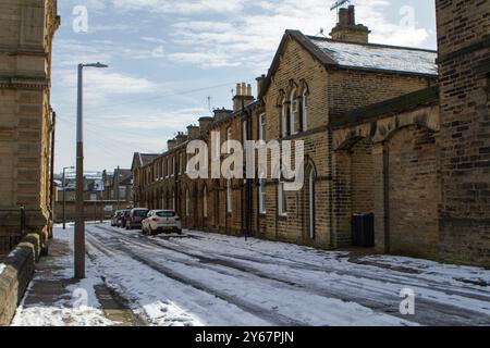 Crogiolandosi al bagliore del sole invernale, questa storica strada di Saltaire si trasforma in un tranquillo paese delle meraviglie. Foto Stock