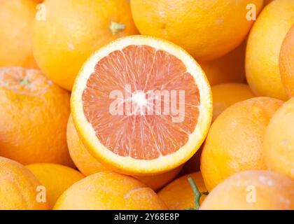 Primo piano su una pila di arance cara, una tagliata a metà per essere esposta al mercato agricolo. Foto Stock
