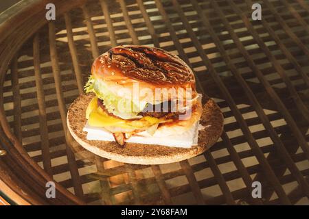 Un primo piano di un hamburger fatto in casa con lattuga fresca, formaggio fuso, cipolle grigliate e una succosa polpetta di manzo in un panino di semi di sesamo, catturata al suo interno Foto Stock