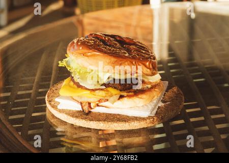 Un primo piano di un hamburger fatto in casa con lattuga fresca, formaggio fuso, cipolle grigliate e una succosa polpetta di manzo in un panino di semi di sesamo, catturata al suo interno Foto Stock