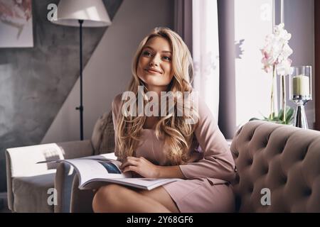 Mi sento calma e felice. Giovane donna attraente che guarda lontano e sorride mentre siede sul divano Foto Stock