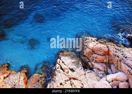 Le acque cristalline si incontrano con un'aspra costa rocciosa, evidenziando la bellezza naturale del Mar Mediterraneo in Turchia. Foto Stock