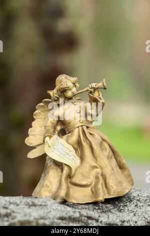 Piccola statua d'angelo che suona il corno dorato sulla tomba nel cimitero di Hietaniemi, Helsinki. L'immagine ha spazio vuoto per il testo. Foto Stock