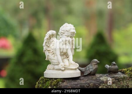 Piccola statua di angelo bianco e due uccelli posti su una lapide. Vecchio cimitero Hietaniemi a Helsinki. L'immagine ha spazio per il testo. Foto Stock