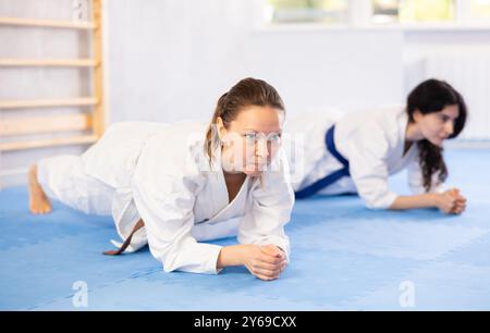 Due donne in kimono che fanno stretching prima di allenarsi con il karate o con il judo Foto Stock