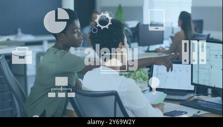 Le icone di business si affacciano su diversi professionisti che lavorano su computer in ufficio Foto Stock