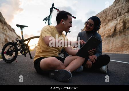 motociclista maschile che usa un tablet in bicicletta con un'amica Foto Stock