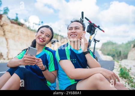 coppia di ciclisti che utilizzano il telefono e le cuffie insieme Foto Stock