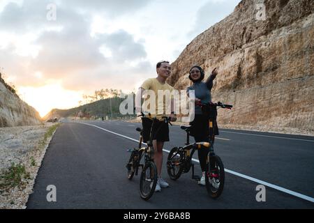 ciclista maschile e femminile in bicicletta con gesto di puntamento Foto Stock