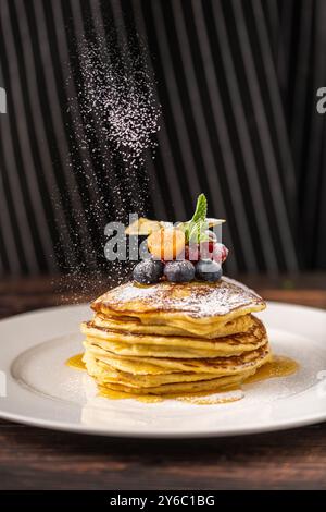 Pancake con frutta e sciroppo d'acero su un piatto bianco Foto Stock