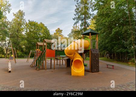 Parco giochi colorato con scivolo e strutture per arrampicate circondate da alberi. Foto Stock