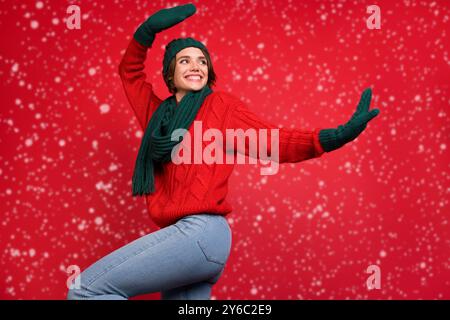 Foto ritratto giovane donna che balla a festa in sciarpa mittens guardando copyspace isolato vibrante colore rosso sfondo Foto Stock