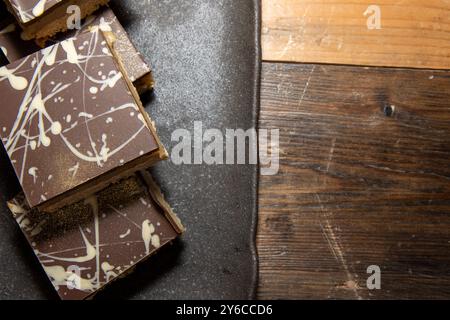 Una deliziosa pila di cioccolatini Millionaires Flapjacks e dolcetti toffee su un piano di lavoro o un tavolo da cucina in legno Foto Stock