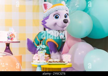 Una colorata festa di compleanno con un personaggio di Paw Patrol con palloncini e decorazioni per torte. Foto Stock