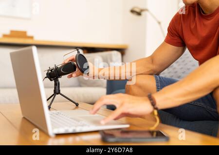 A casa, impostare il microfono, l'uomo che usa il laptop e si prepara per la registrazione del podcast Foto Stock