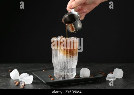 Donna che prepara rinfrescanti bevande toniche per espresso al tavolo buio, primo piano Foto Stock