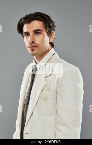 Un uomo giovane e affascinante sfoggia un abbigliamento formale elegante e una posa sicura in uno studio moderno. Foto Stock
