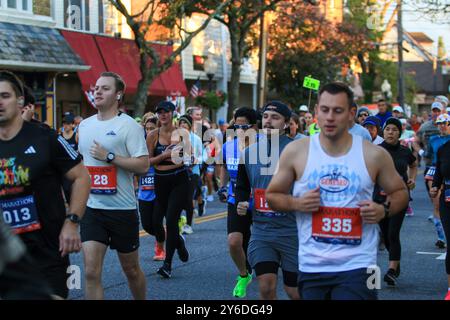 Babylon, New York, Stati Uniti d'America - 22 ottobre 2023: Un grande gruppo di corridori che corrono in una maratona e mezza maratona lungo la strada principale del Babylon Village. Foto Stock