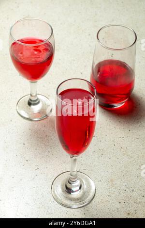 Ritratto dall'alto, tre bicchieri pieni di vino rosso sono su un tavolo di granito con texture terrazzo Foto Stock