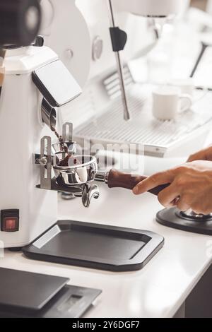 Il macinacaffè automatico eroga senza sforzo i fondi di caffè freschi nel portafiltro Foto Stock
