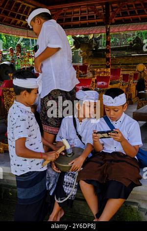 Indonesia, Bali, città di Ubud, tempio pura Samuan Tiga, bambini e telefono cellulare Foto Stock