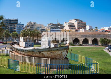 Città vecchia di Heraklion, vista di un peschereccio d'epoca e dei resti di capannoni di navi del XVI secolo - gli Arsenali - nel porto veneziano di Creta Foto Stock