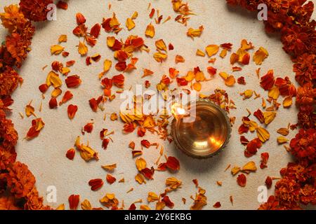 Festa Diwali. Lampada Diya e splendidi fiori su sfondo chiaro, vista dall'alto Foto Stock