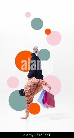 Uomo, breakdancer in piedi da una mano, che stringe borse della spesa piene di offerte del Black Friday su sfondo bianco con elementi colorati Foto Stock