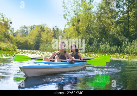 Gita in kayak per tutta la famiglia, madre e figlia che pagaiano in kayak su un tour in canoa sul fiume divertendosi, weekend autunnale attivo e vacanze con bambini Foto Stock