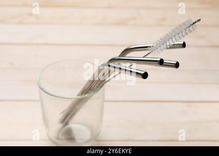 Cannucce di metallo e spazzolina per la pulizia in vetro su un tavolo di legno, primo piano Foto Stock