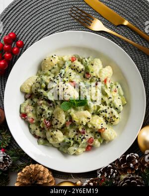 Gnocchi deliziosi con salsa di yogurt e asparagi verdi. Tavolo con vista dall'alto e decorazioni natalizie. Foto Stock