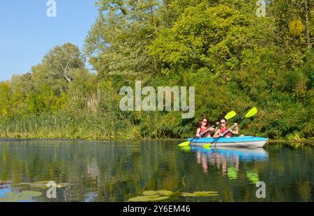 Gita in kayak per tutta la famiglia, madre e figlia che pagaiano in kayak su un tour in canoa sul fiume divertendosi, weekend autunnale attivo e vacanze con bambini Foto Stock