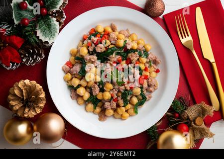 Salsiccia di maiale catalana con ceci e spinaci. Tavolo con vista dall'alto e decorazioni natalizie. Foto Stock